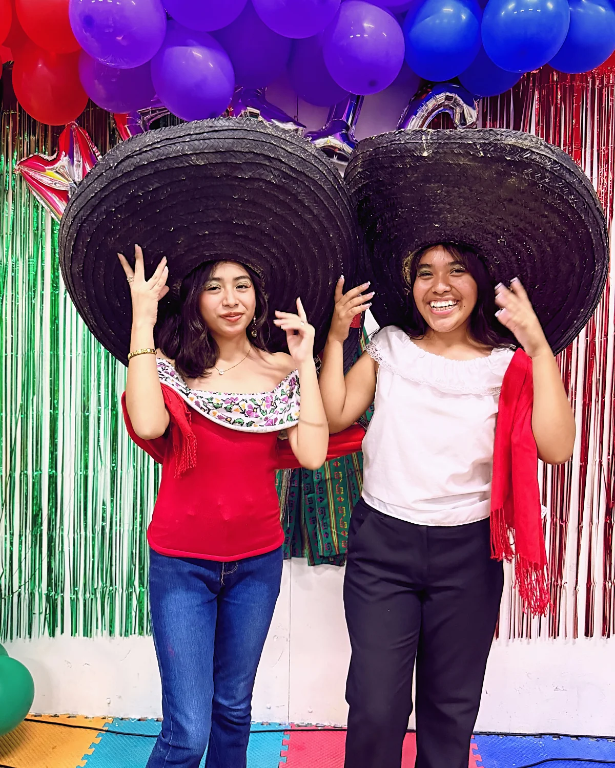 Dos jóvenes de Hope City sonríen con sombreros gigantes en la Fiesta Mexicana